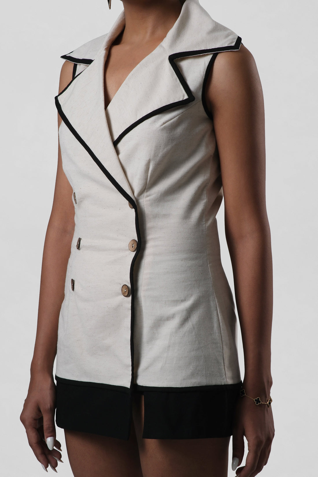 Close-up of the Amelia Dress in natural linen highlighting oversized lapels, six coconut shell buttons, princess seam tailoring and contrast black canvas edging.