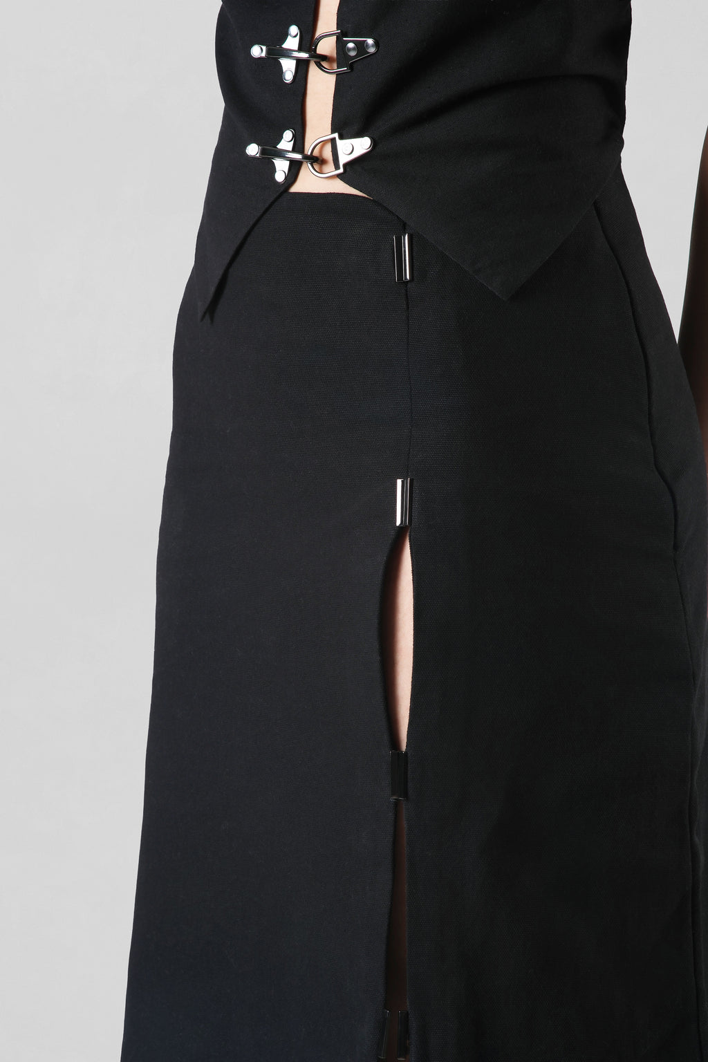 Elizabeth Skirt in black crafted from premium cotton canvas featuring a tailored midi silhouette with a contemporary front slit.